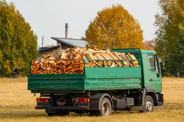 Green truck loaded with split firewood