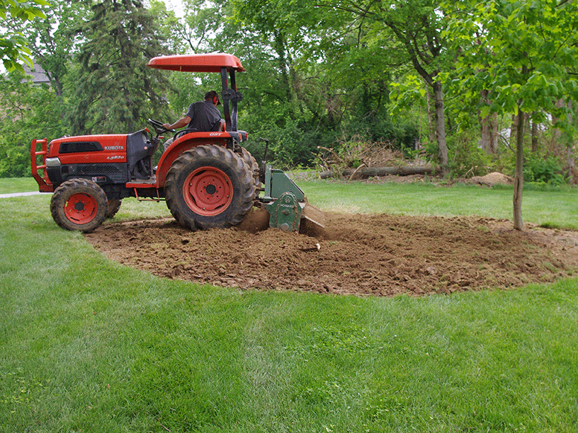 Motz equipment grading soil around an established residential landscape