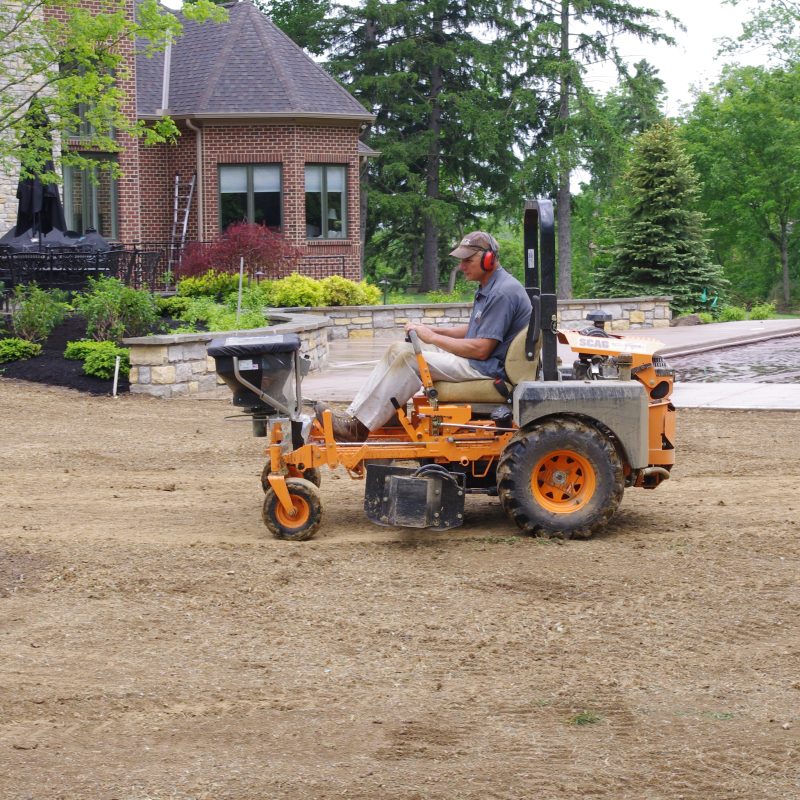 Motz equipment professionally applying grass seed to a prepared residential lawn